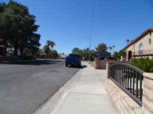 Suburban street with blue truck and palm trees, sunny day