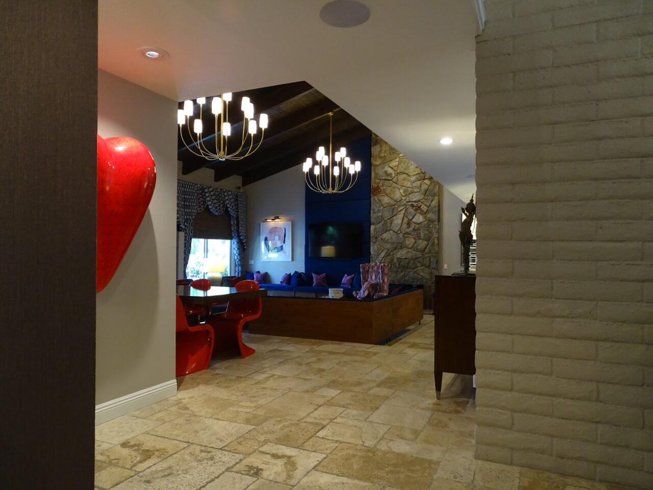 Modern living room with chandeliers and red chairs.