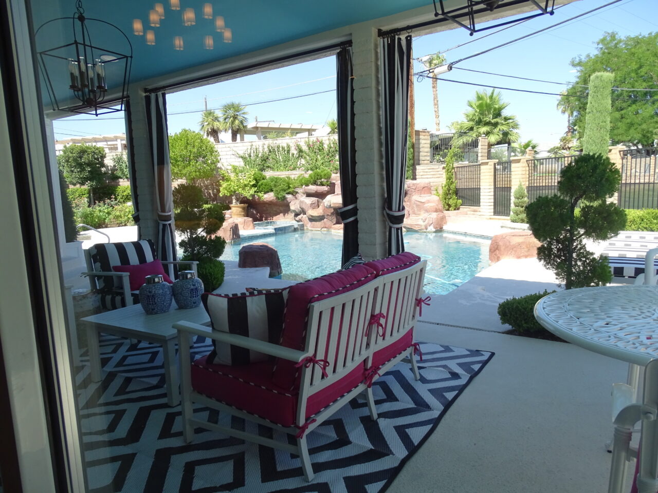 Covered patio with stylish furniture overlooking a pool.