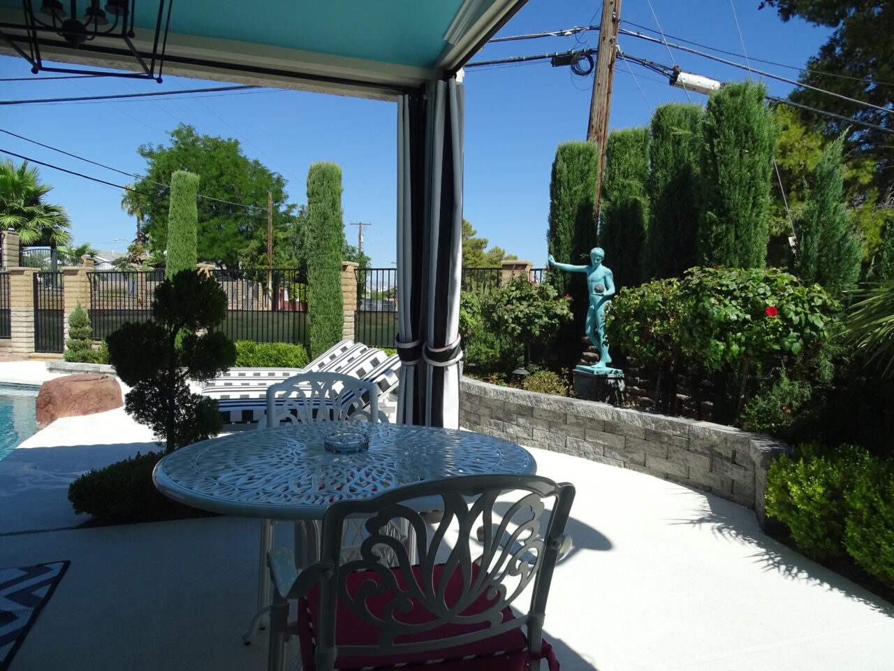 Backyard patio with pool, statue, and dining set.