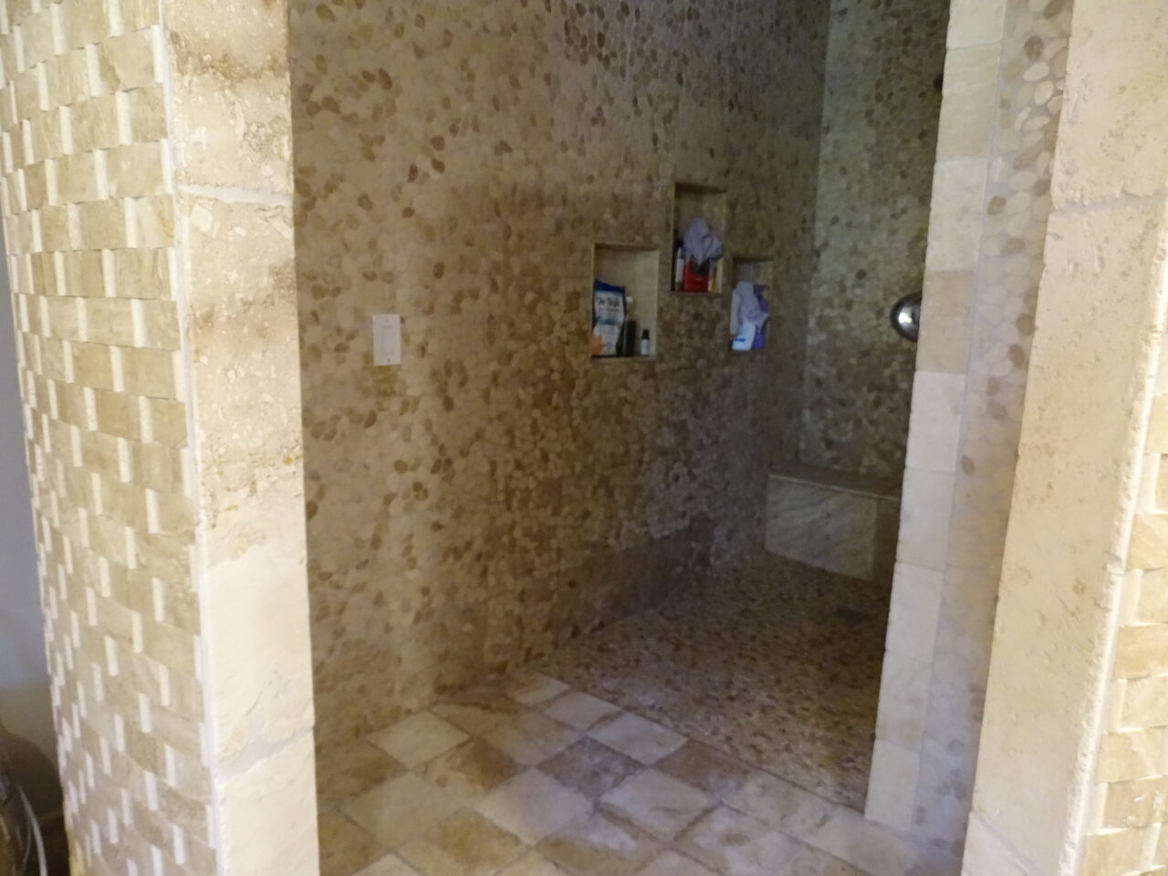 Stone wall corridor with recessed nooks and light fixtures.