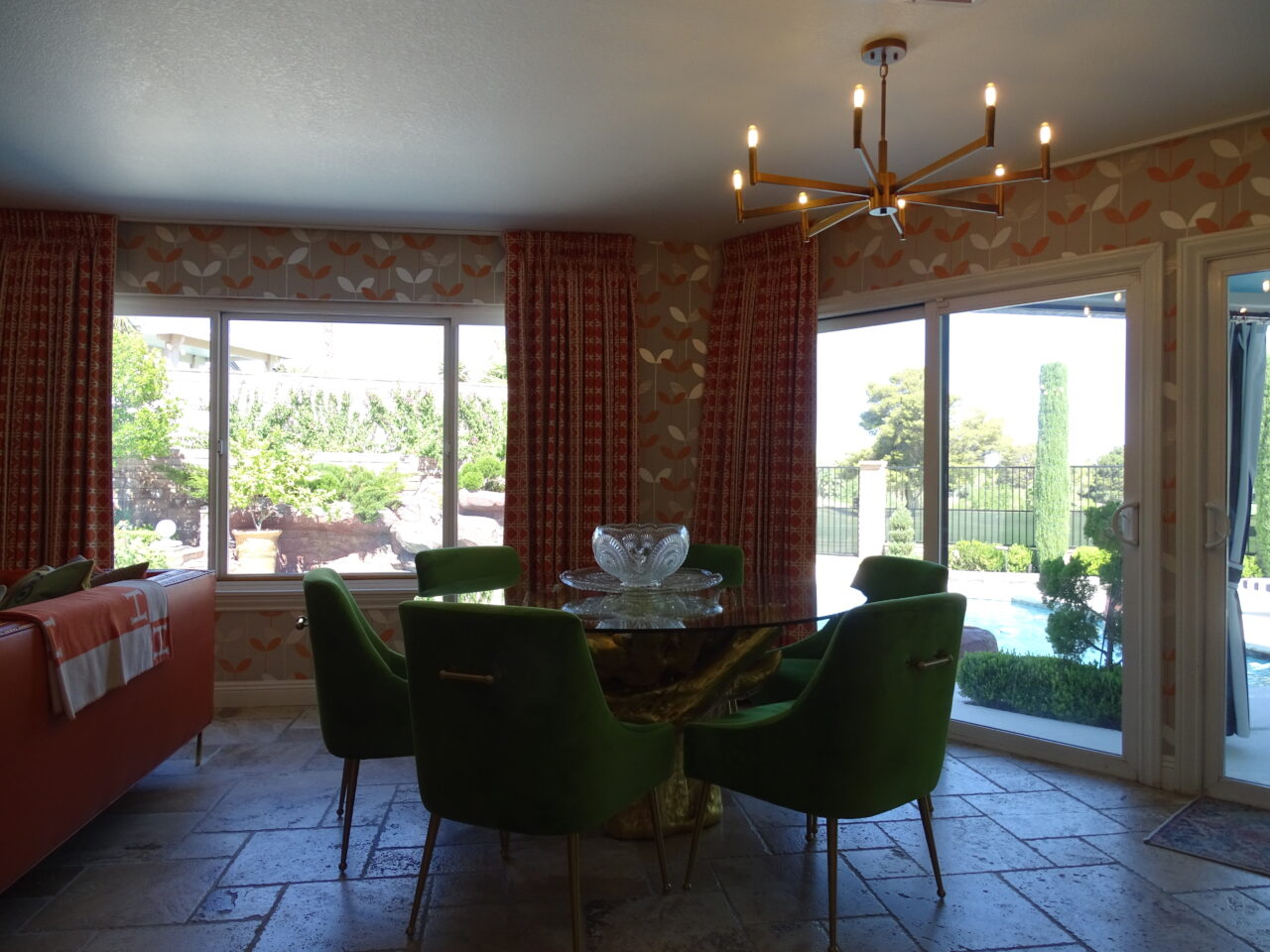 Bright, stylish living room with green chairs and pool view.