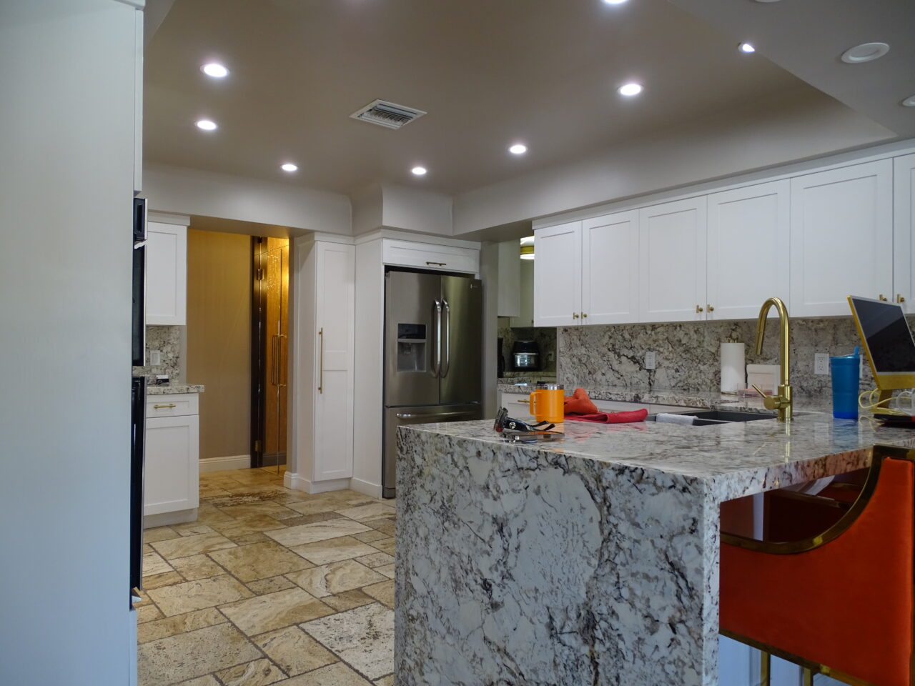 Modern kitchen with marble island and white cabinets.