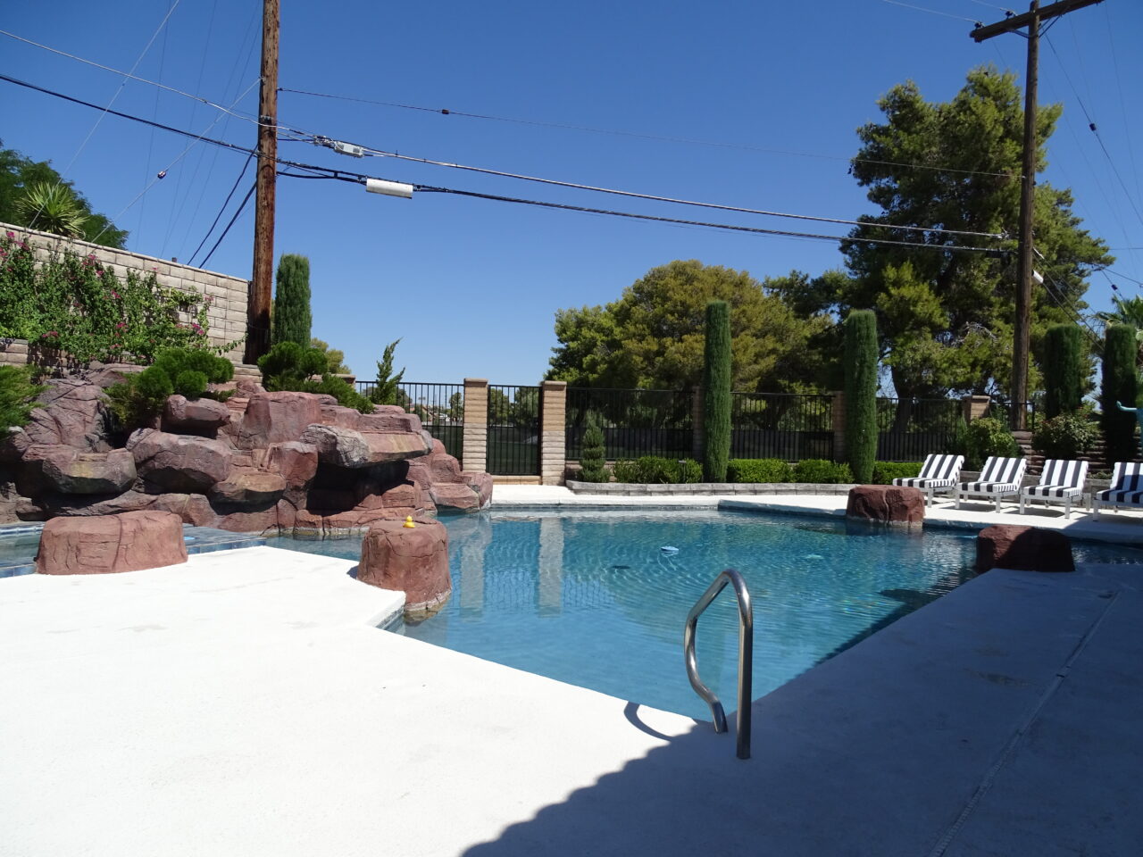 Outdoor pool with rock waterfall and lounge chairs.