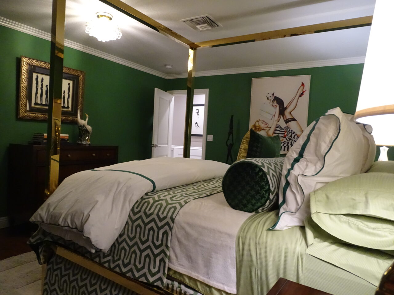 Elegant green bedroom with gold-framed bed and art decor.