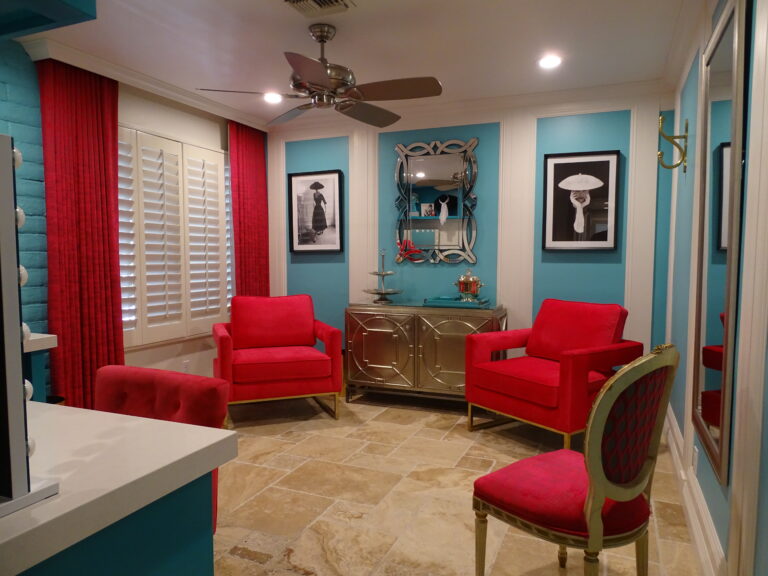 Colorful living room with red chairs and teal walls.