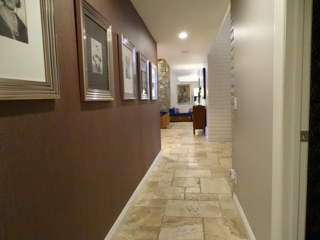 Elegant hallway with stone flooring and framed artworks.