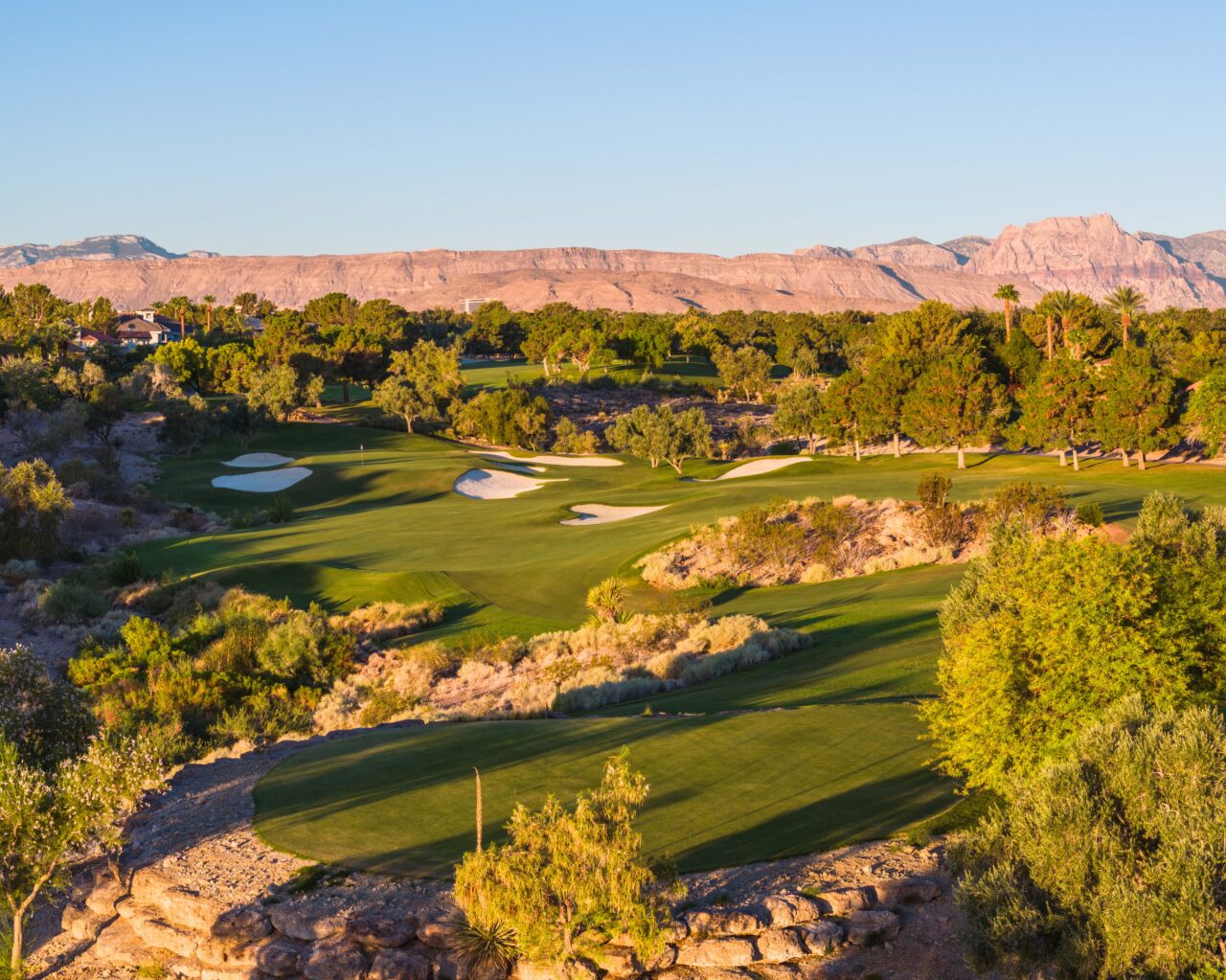 Scenic golf course with mountains in background at sunset