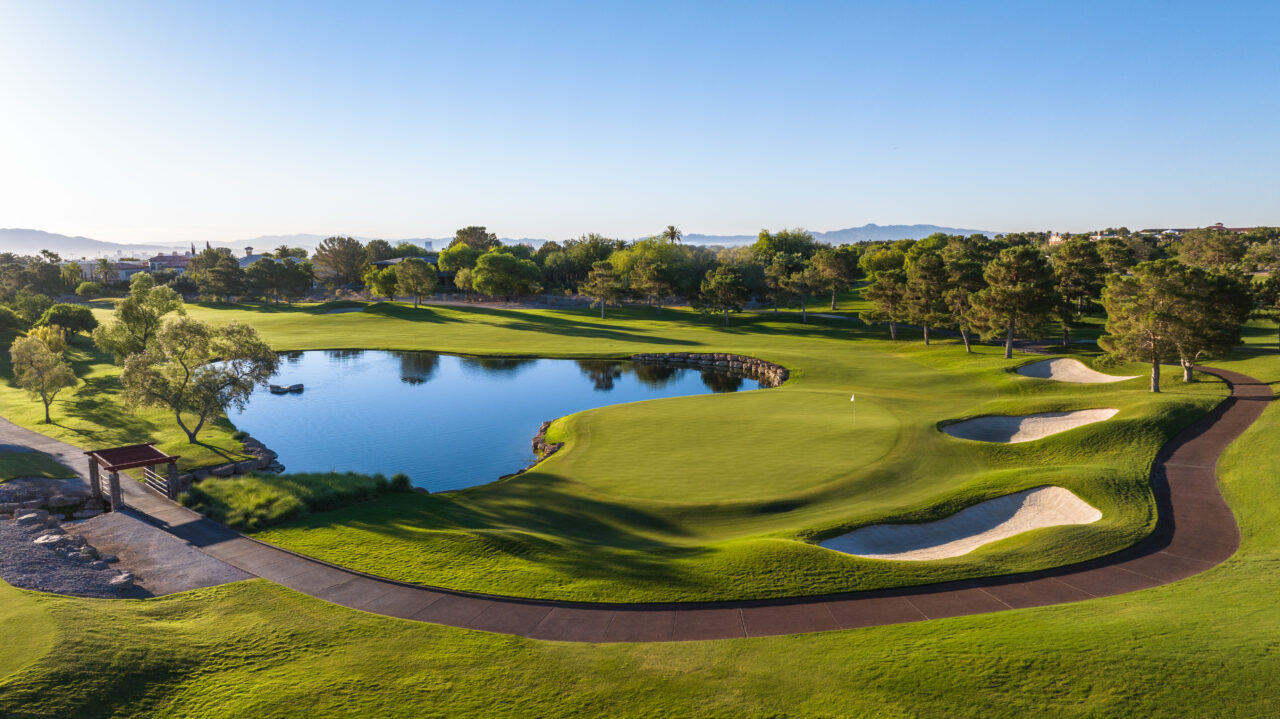 Aerial view of sunny golf course with pond