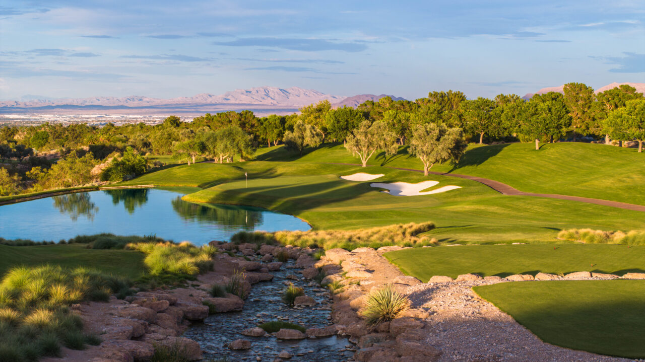 Scenic golf course with water hazards and mountain backdrop