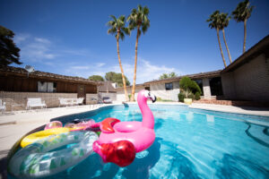 Sunny poolside with pink flamingo float and palm trees