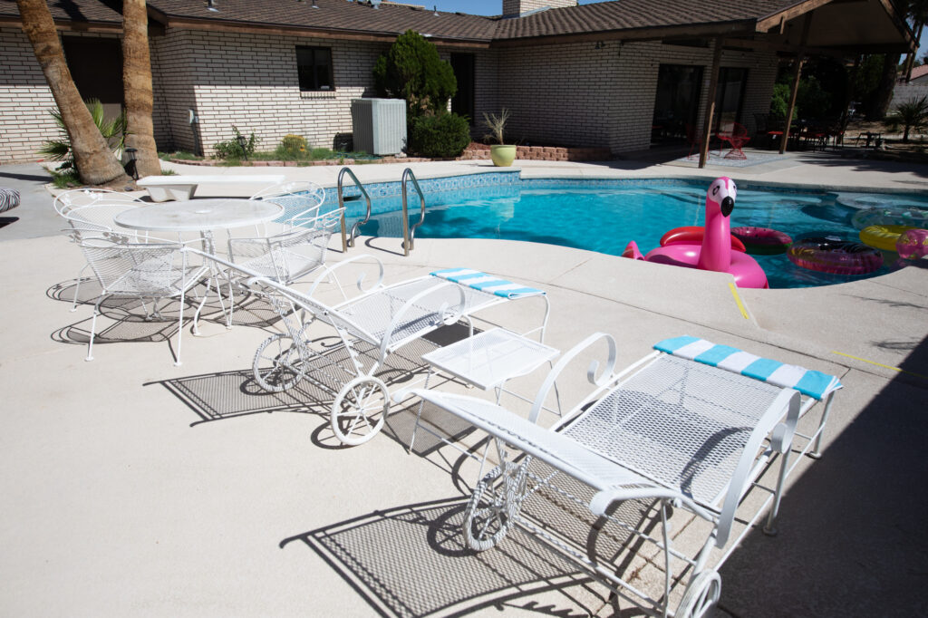 Sunny poolside area with white patio furniture and floats