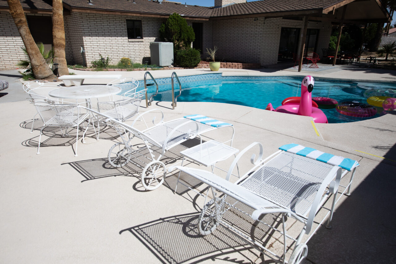 Sunny poolside area with white patio furniture and floats