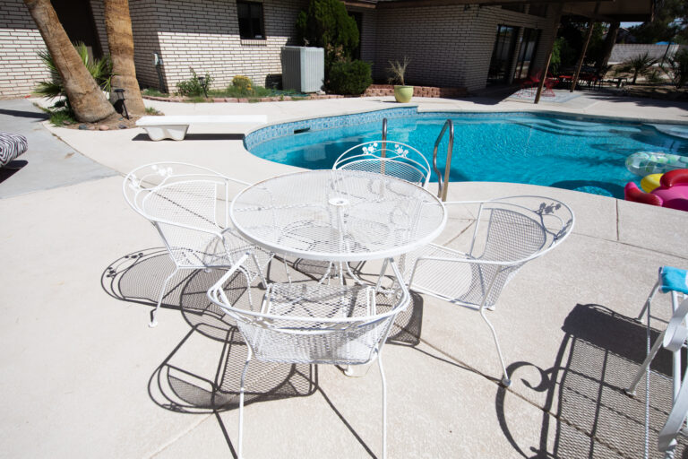 Sunny poolside with white metal patio furniture