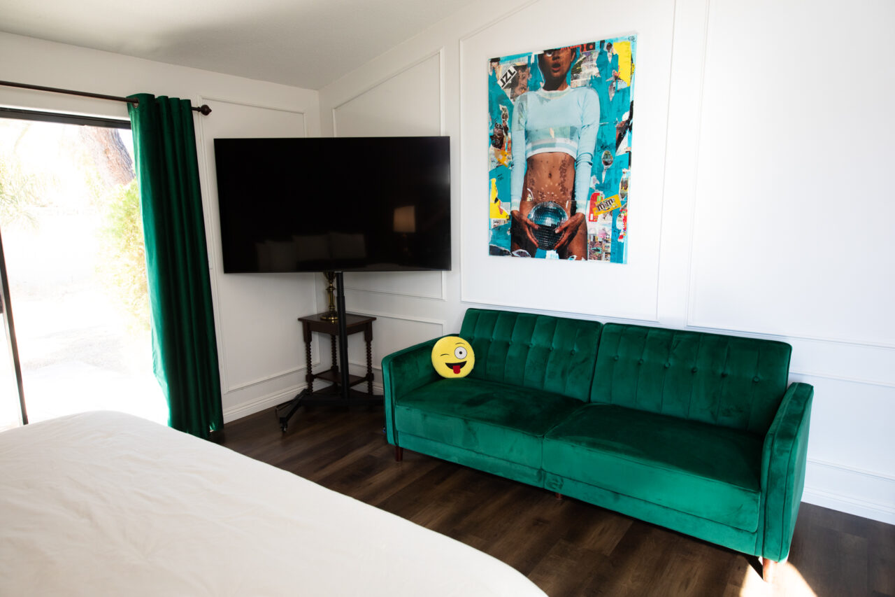 Modern bedroom with green sofa and large flat-screen TV