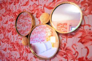 Room with flamingo wallpaper and circular mirrors